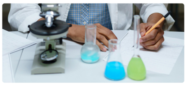 biophysicist writs on paper with colored beakers in foreground